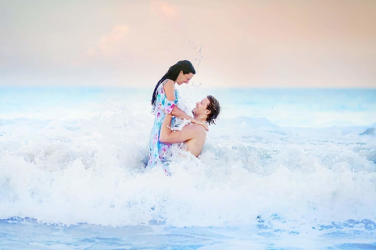 Couple lifts each other out of the ocean and their Maui engagement portraits in the ocean