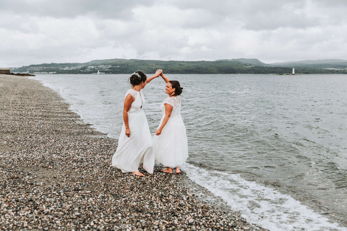 two brides dancing on the beach