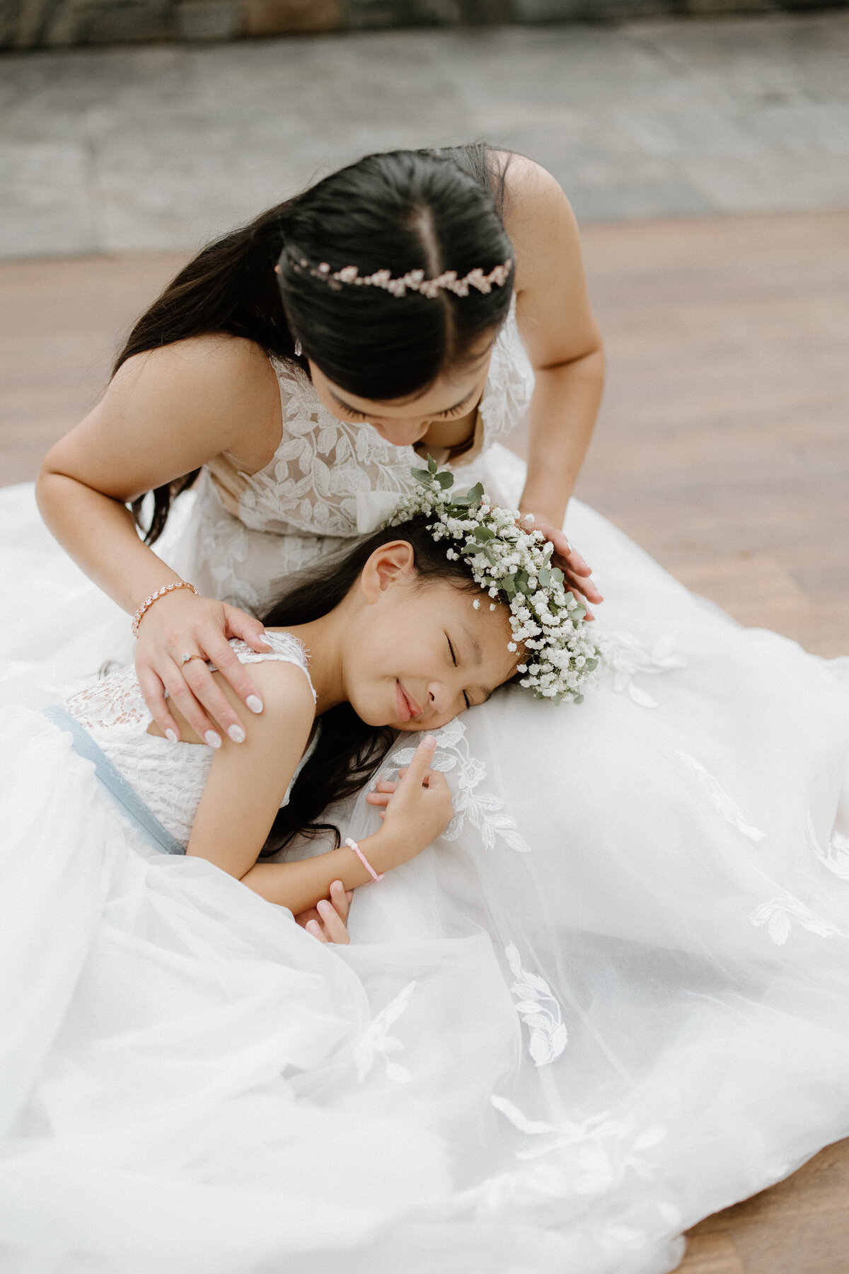 The bride looking at her daughter fondly as the child lays happily in her lap