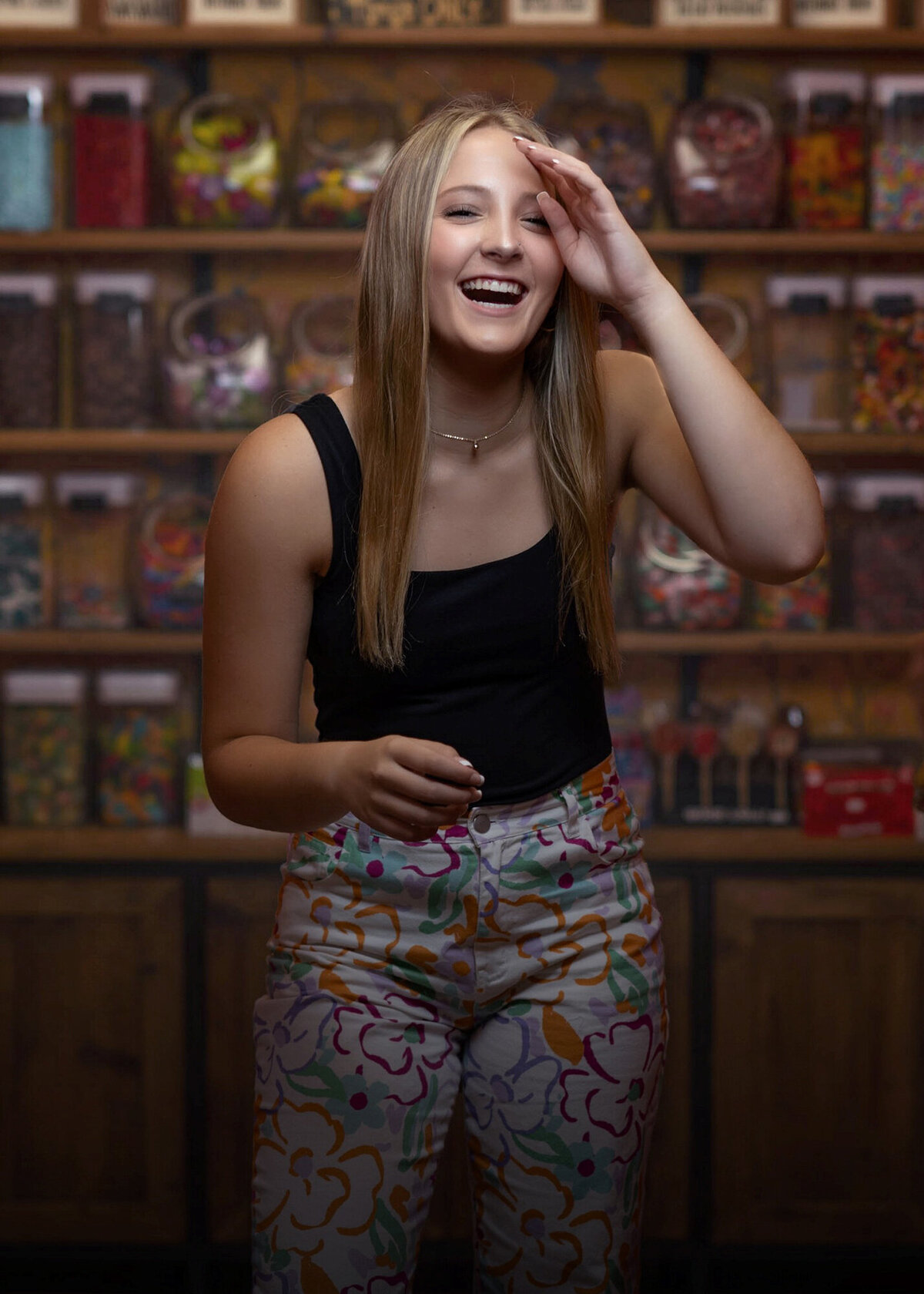 A senior laughs while shopping in a candy store in a black top