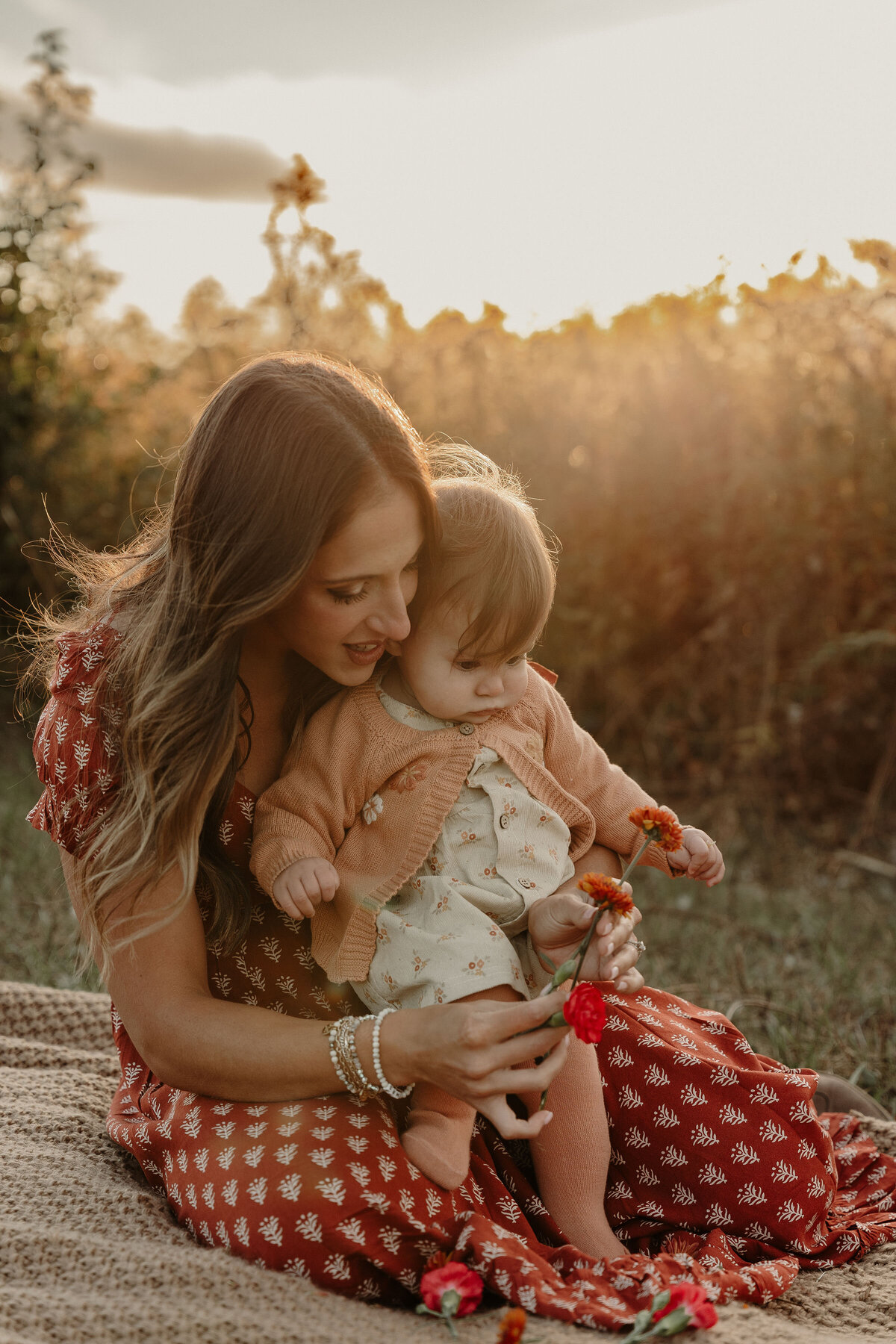 Mom and baby looking at red flowers