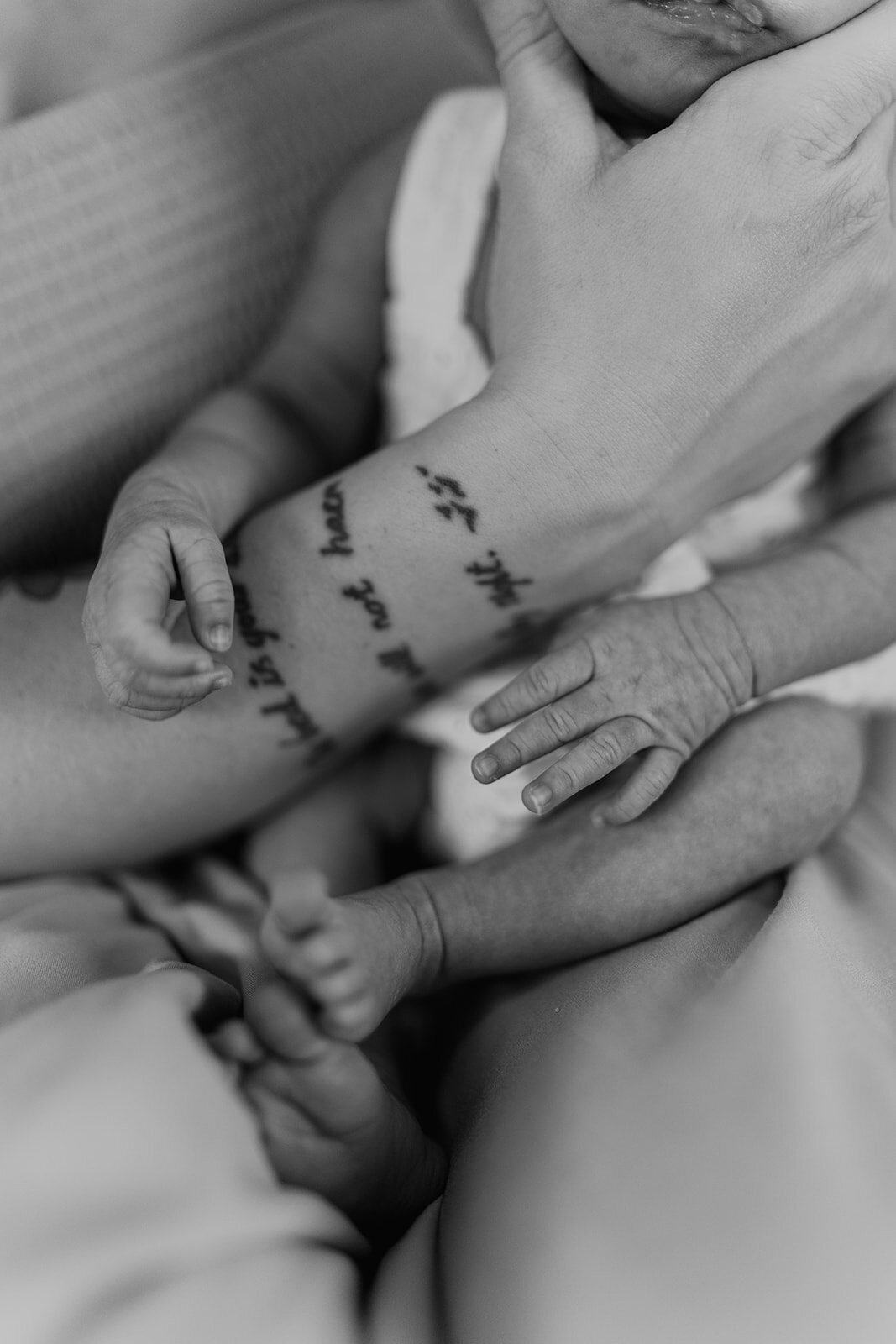 iconic newborn's tiny hands and feet next to mom's tattoo