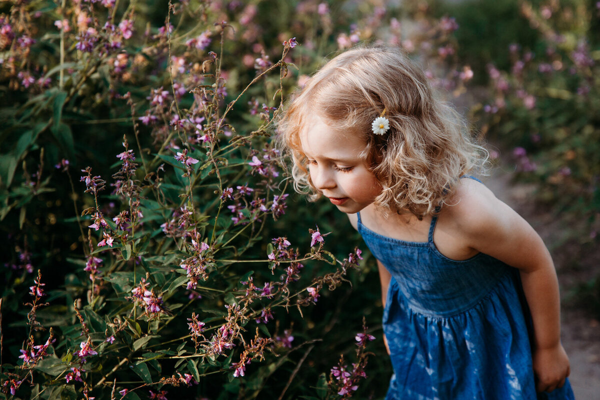 Curly haired blond girl smelling some flowers during her family photography session in Toronto