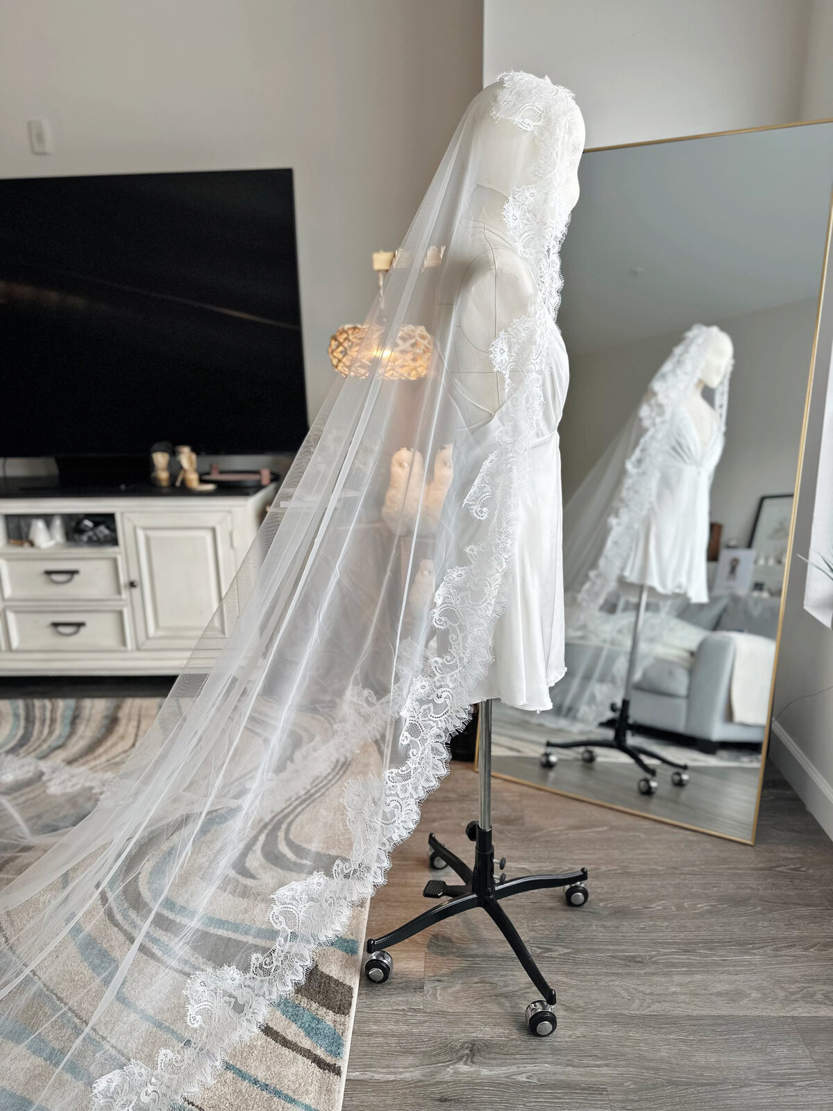 Bride adjusting lace mantilla veil during morning wedding prep