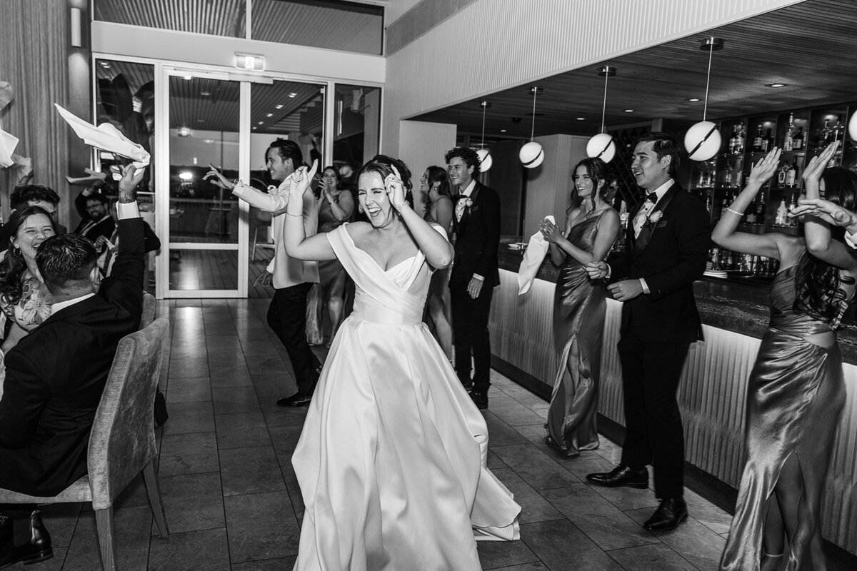 Bride cheering during her wedding reception grand entrance! Pictured by the bar at The Marion, an exceptional wedding venue in Canberra ACT