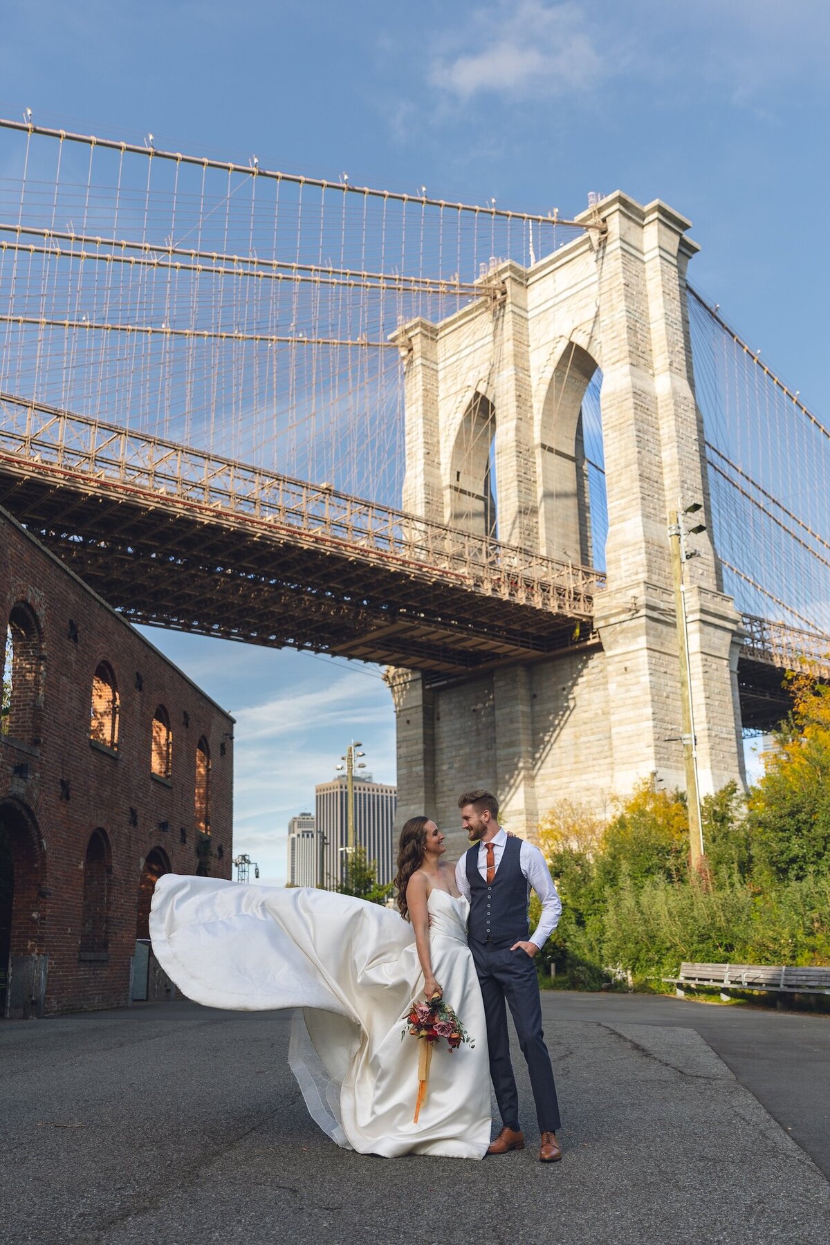 Bride and groom embracing beneath the Brooklyn Bridge