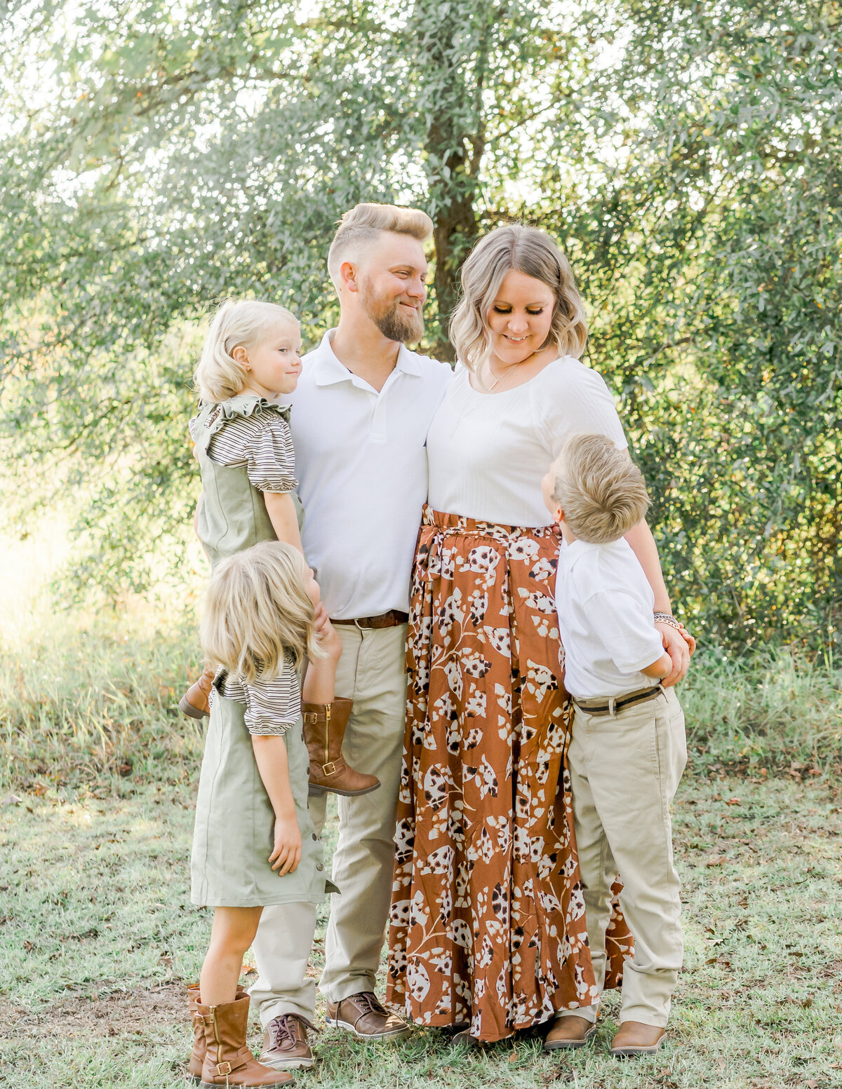mom engaging with and smiling at son while entire family is hugging while observing at Christmas mini session