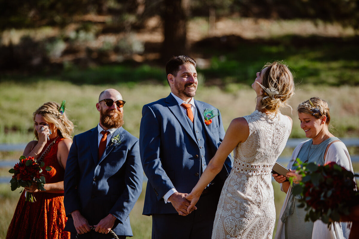 Two marriers laugh during their wedding ceremony, while others around them laugh and cry.