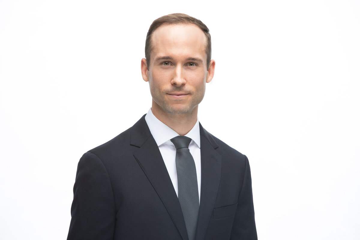 A businessman in a blue suit jacket poses for a professional headshot on a white background for Janel Lee Photography studios in Cincinnati Ohio