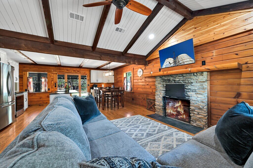 Living area with ample seating and fireplace in this four-bedroom, three-bathroom cabin with private garage, firepit, grill, and wi-fi just outside of Waco, TX