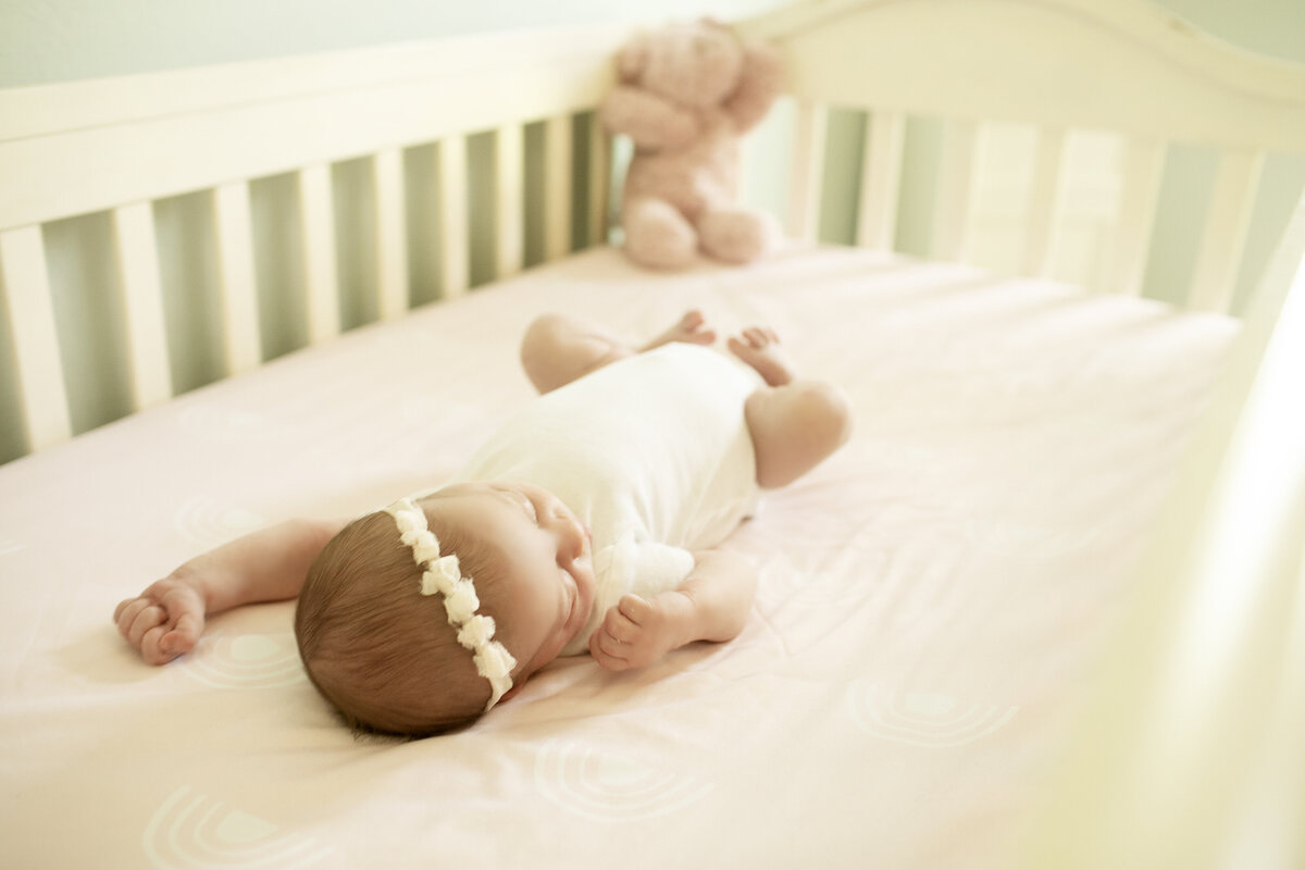Newborn baby girl peacefully resting in a crib, surrounded by soft blankets, creating a cozy and serene scene