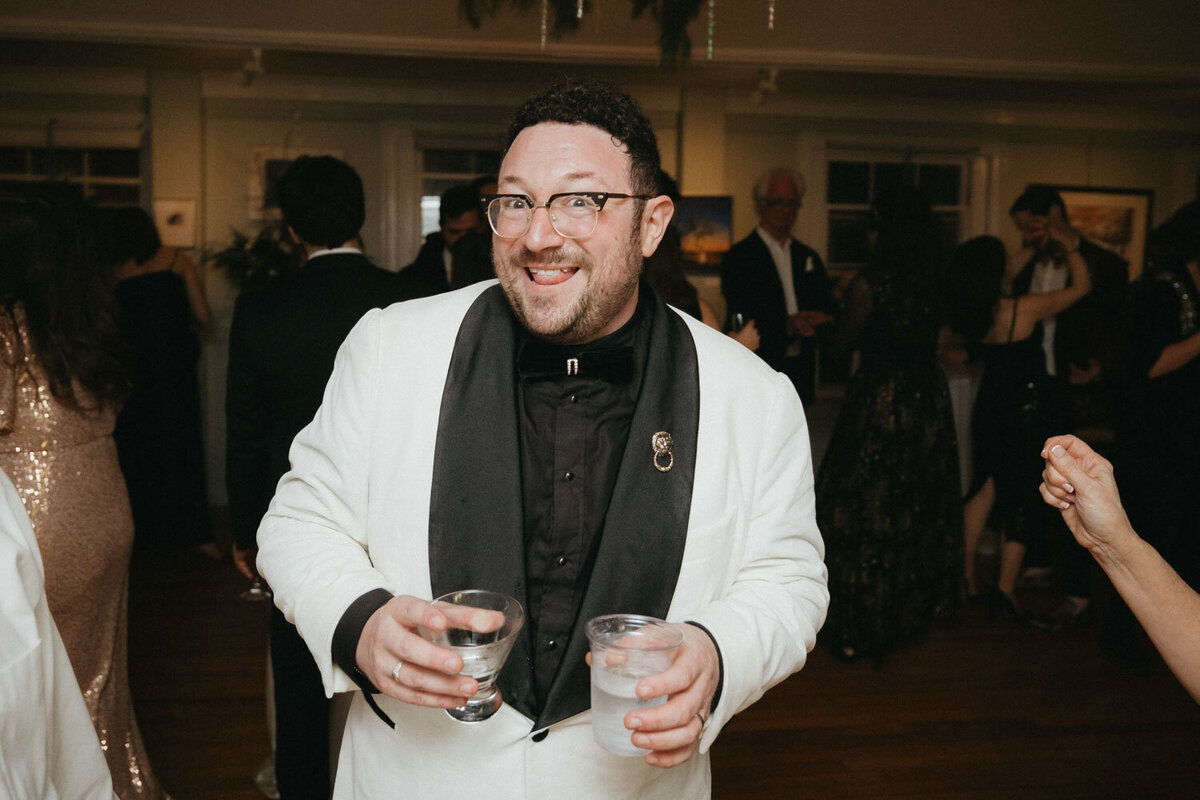 Groom holding glass in each of his hands