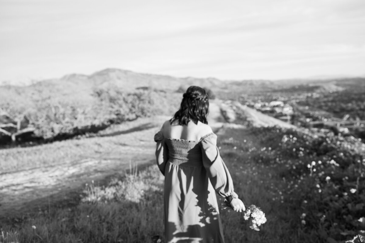 woman walking through a field in a sundress