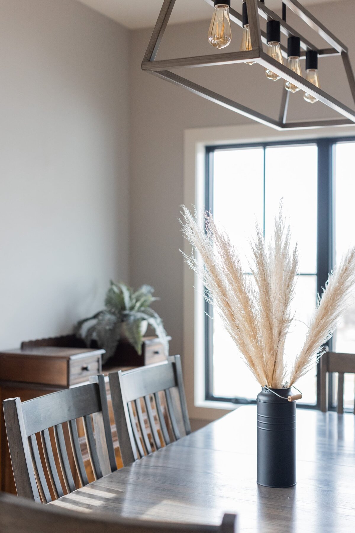 michele rosenboom design modern farmhouse dining table with light fixture and black vase on table