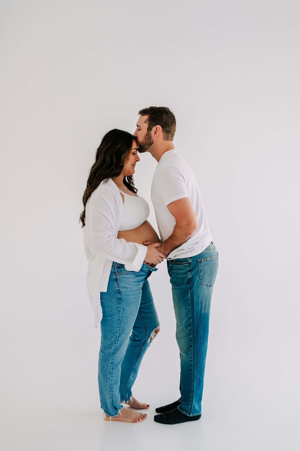 Branson maternity photographer captures husband kissing pregnant mom forehead holding baby bump