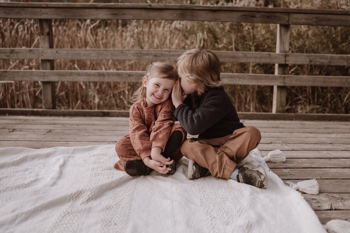 siblings sitting on boardwalk