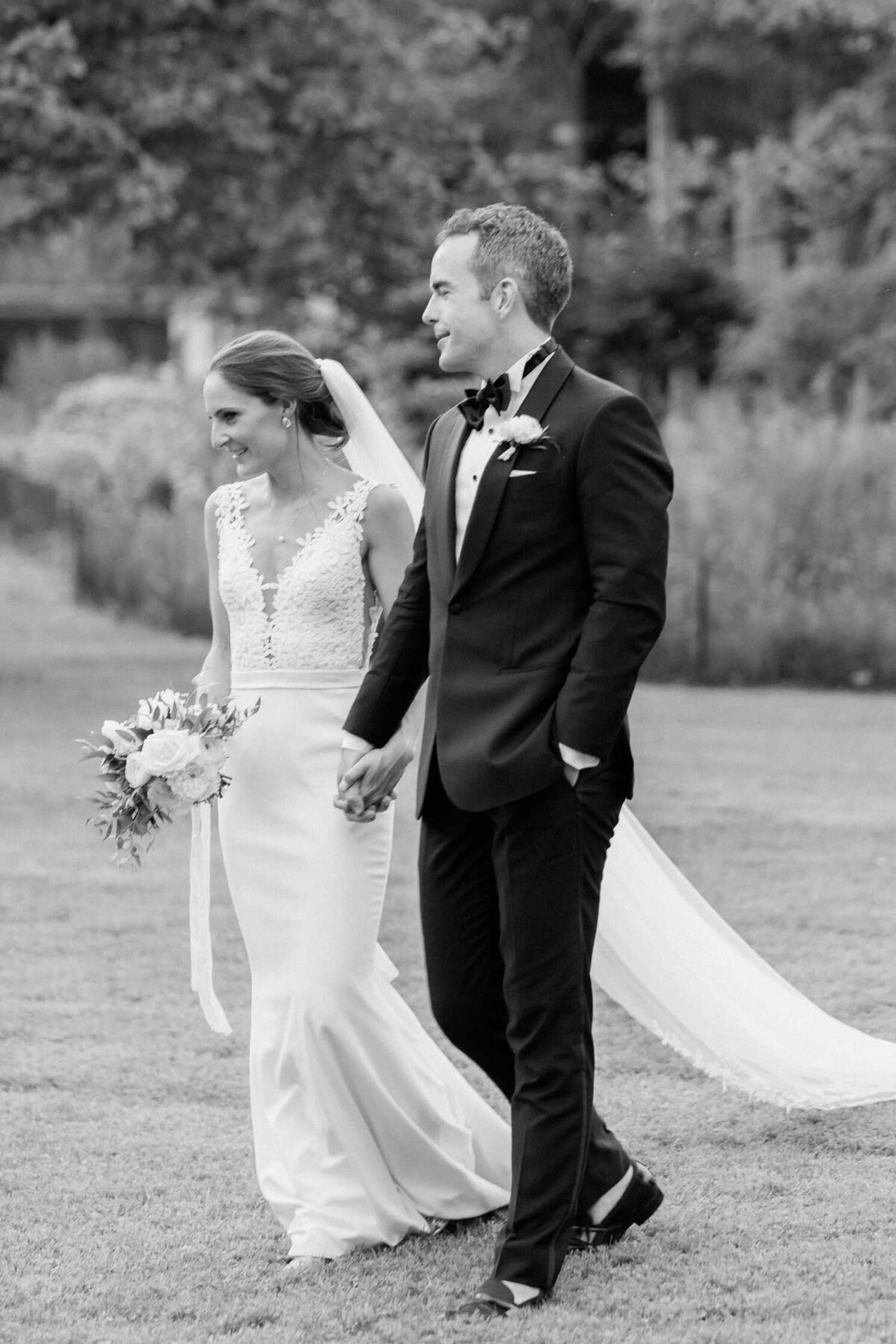 Black and white bride and groom photo walking through the garden outside their Luxury Chicago Outdoor Historic Wedding Venue.