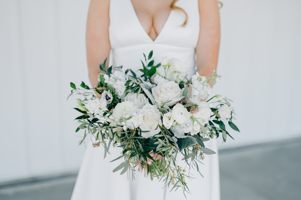 Bride holds her all white and green bouquet at her Midwest wedding in Omaha NE. Photo by Anna Brace, one of Omaha Wedding Photographers.