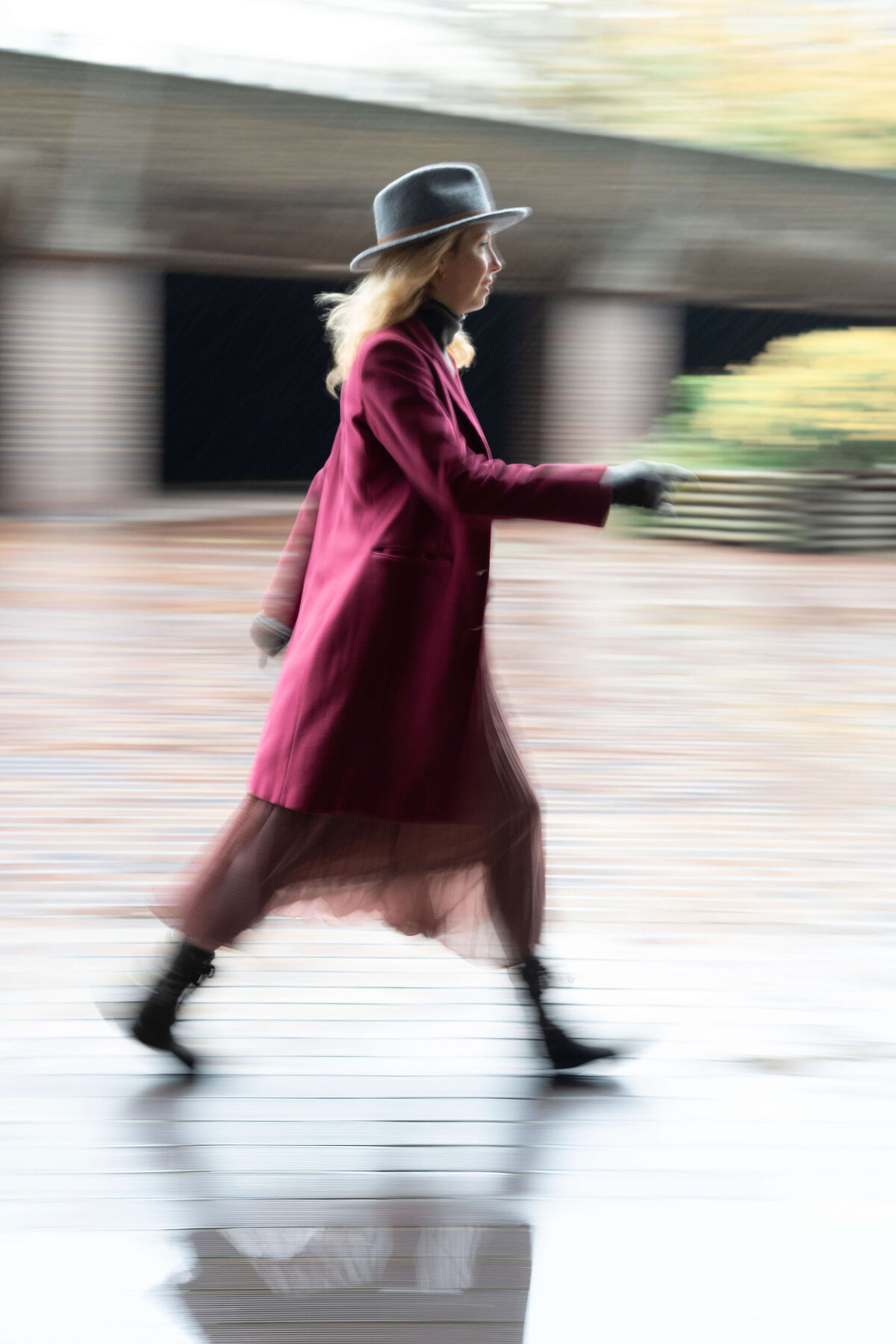 a woman in a bright pink coat walking in the rain in the streets of London 
