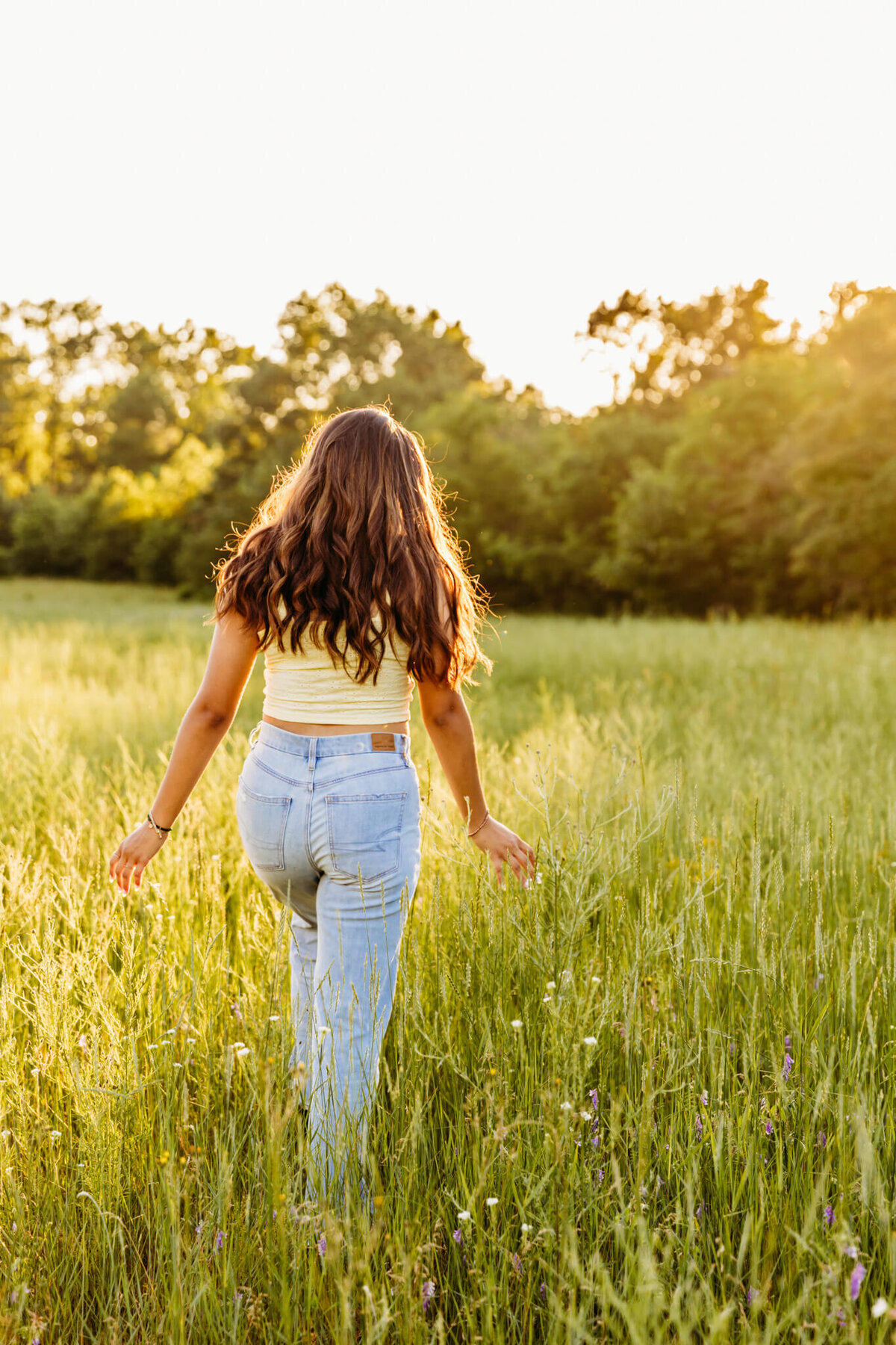 image of a girl in jeans walking towards the tress in a park just outside of Oshkosh