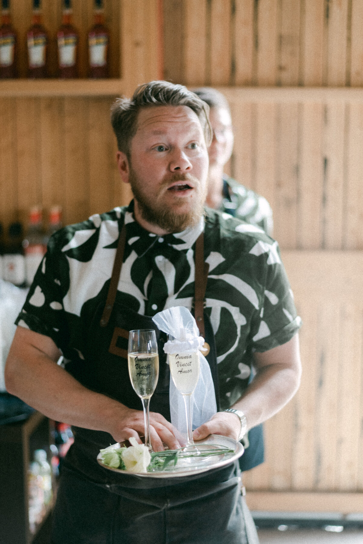 A waiter holding two glasses of sparkling photographed by wedding photographer Hannika Gabrielsson