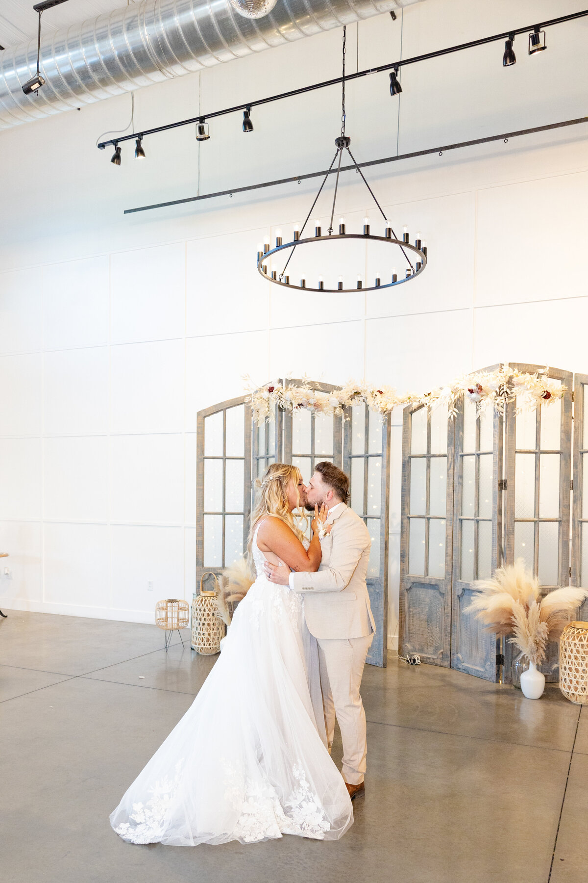 The newlyweds share their first dance under a grand chandelier, framed by elegant wedding decor.