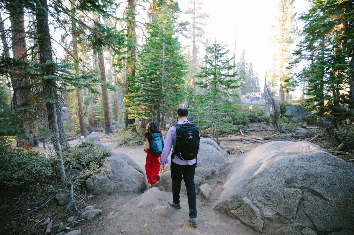 man and woman hike with backpacks on a trail in a forest
