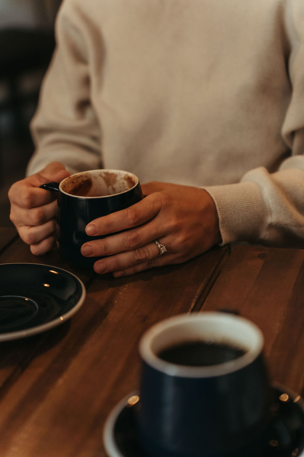 Photo of woman holding coffee mug, with focus on engagement ring