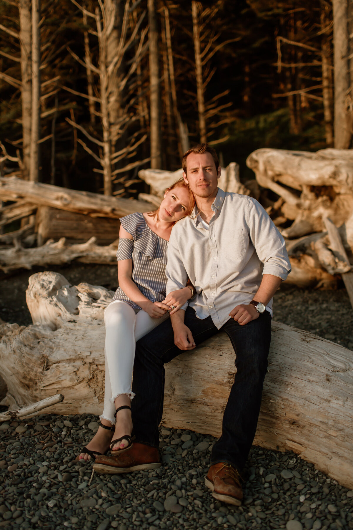 A romantic moment of a couple sitting on driftwood at sunset captured by Fort Worth Wedding Photographer, Megan Christine Studio