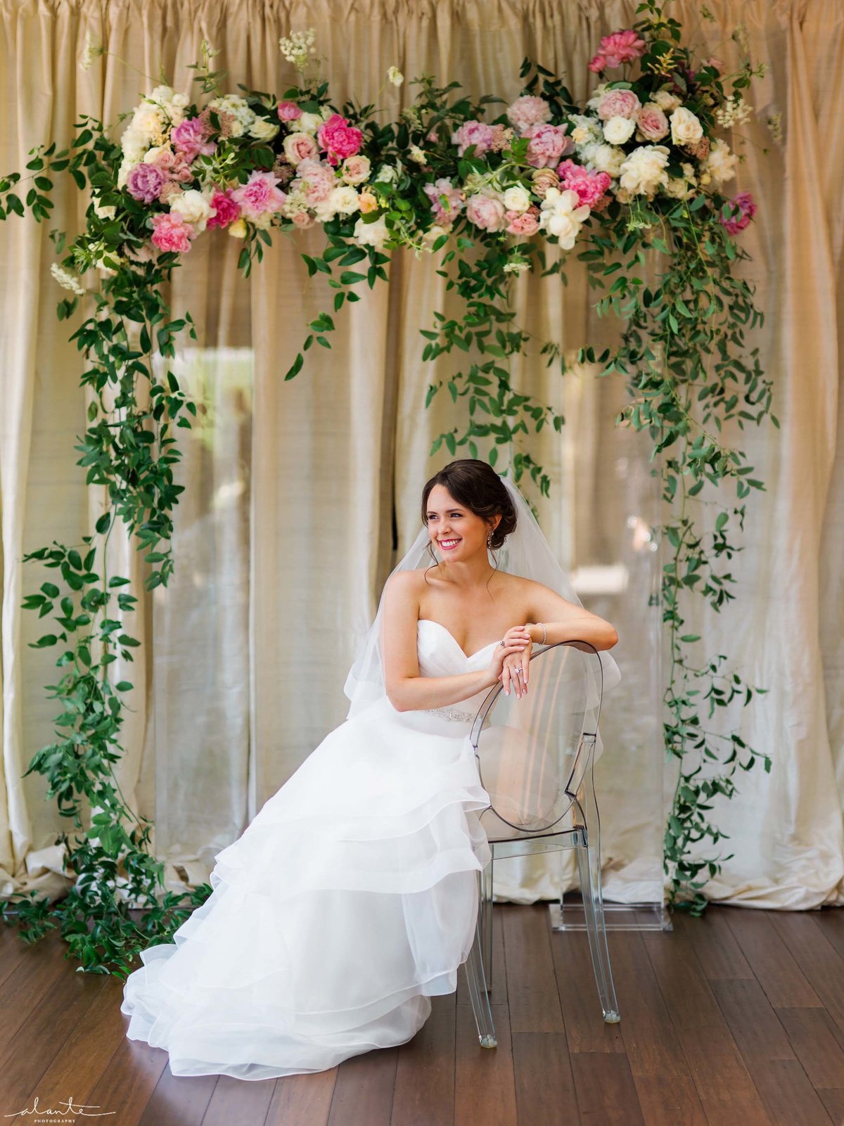 Stunning lucite wedding ceremony arch with smilax and blush peonies.