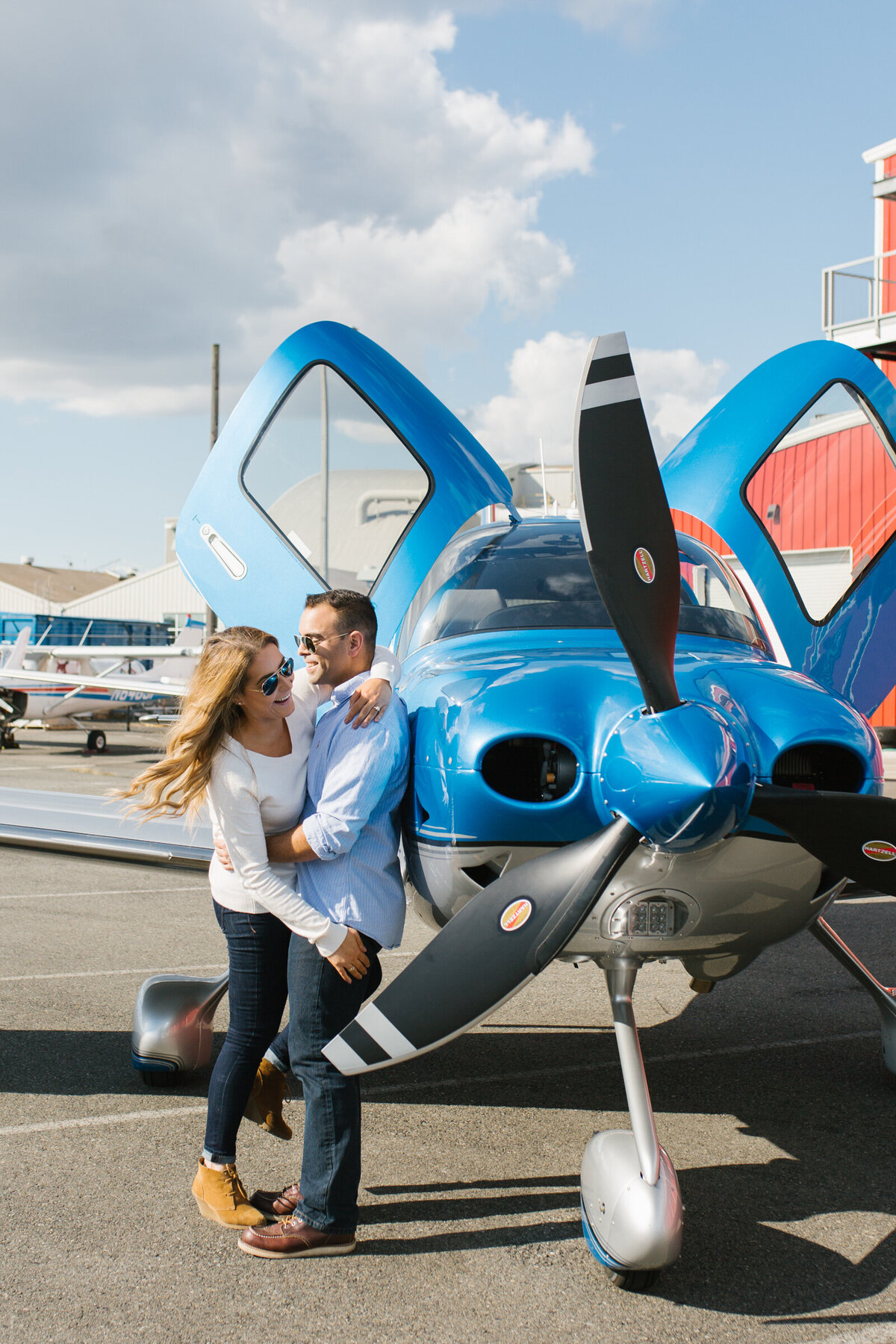 An engaged couple standing next to a prop plane in Seattle for their engagement session.