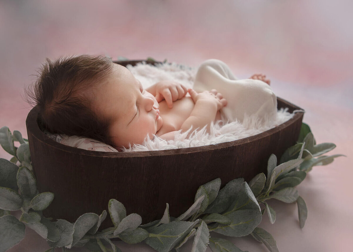 Baby asleep in a wooden heart bowl with image created by LA newborn photographer