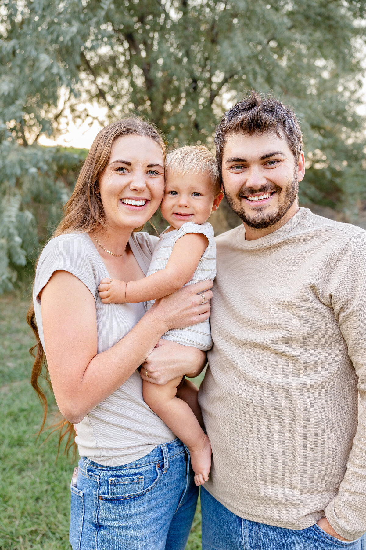 A cheerful mother, father, and their little one sharing a warm embrace with nature as the perfect backdrop.