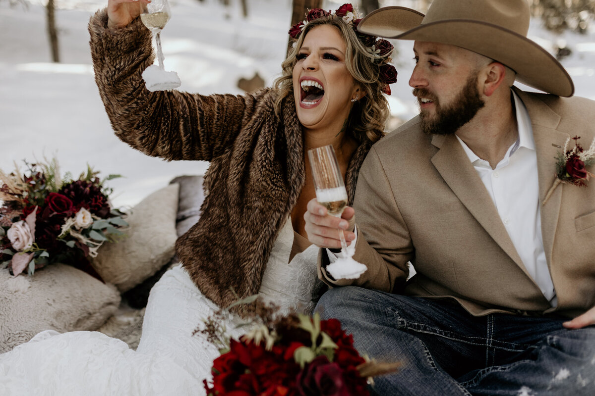 bride and groom drinking champagne in the snow