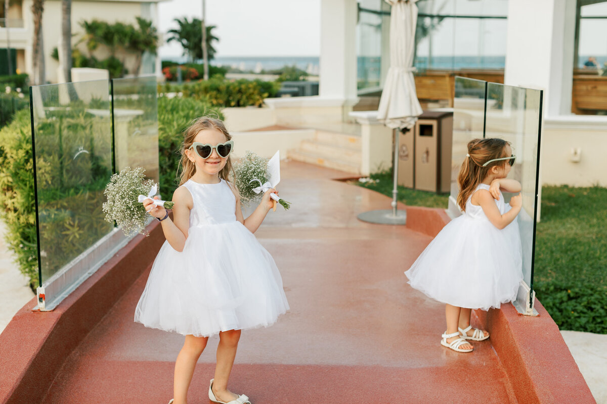 Flower girls in white dresses and sunglasses at a beachside Cancun wedding, photographed by Philly photographer.