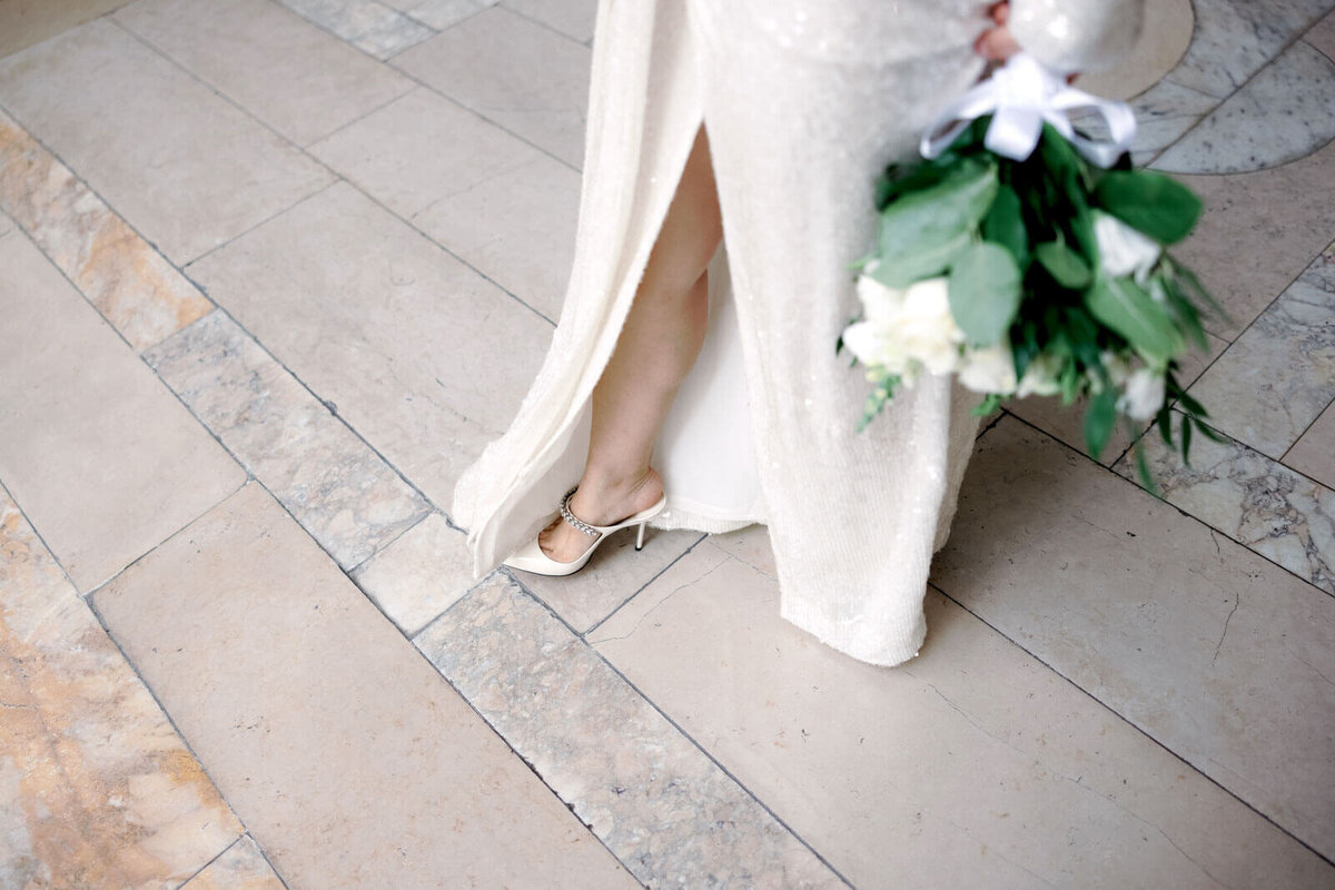 A lower half-body shot of the bride, shoes and flower bouquet are seen, in the New York Public Library. Image by Jenny Fu Studio
