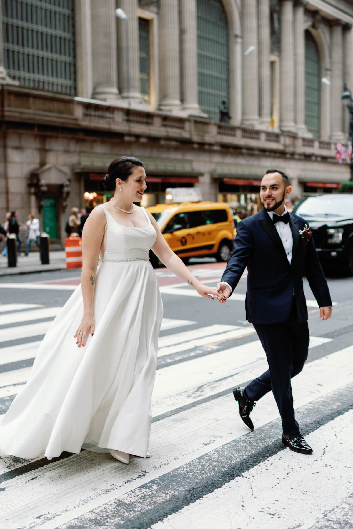 NYC wedding couple walks across street with yellow cab in the background
