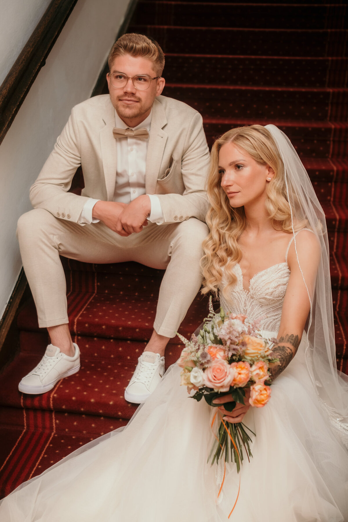 Bride and groom sit on stairs looking sidewards - wedding photography.