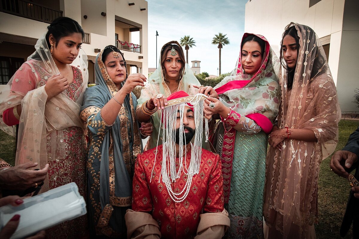 Sikh Groom getting veil placed on him by sisters.