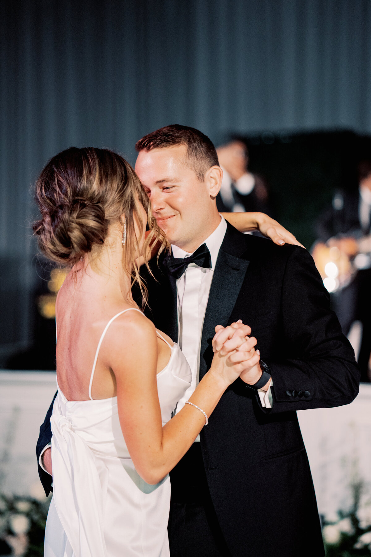 A romantic close-up of the bride and groom’s first dance, showcasing deep emotions and elegant wedding attire.