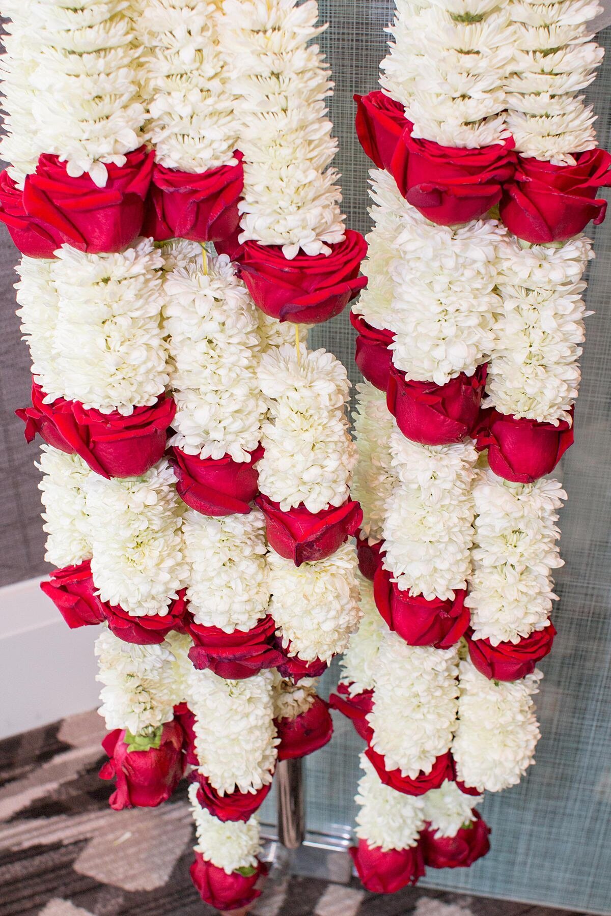Two varmala garlands made of mums accented with red roses.