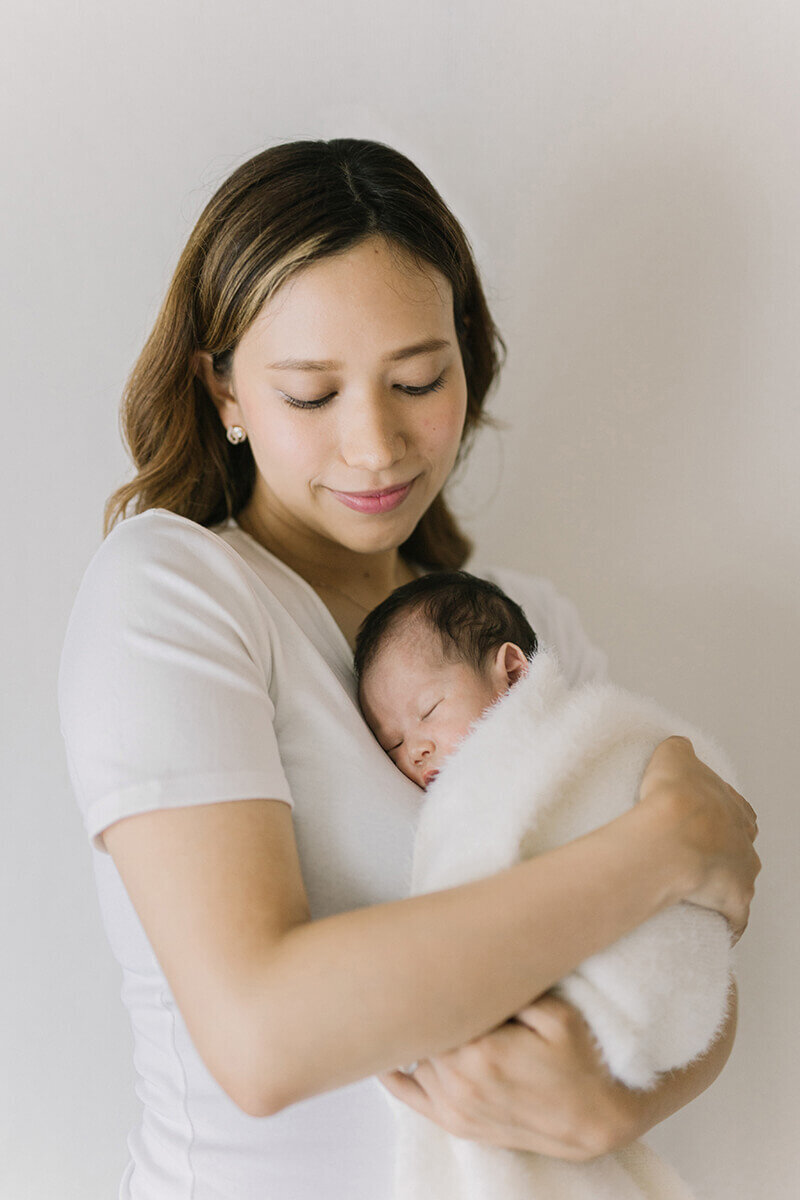 Mother is holding baby on her chest. Newborn photography in Tokyo. The shot was taken in Yokohama.