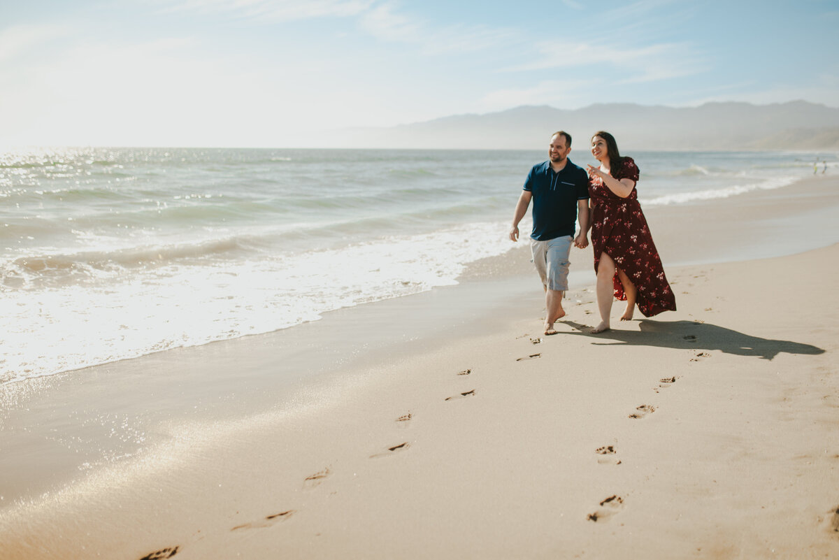 destination wedding photographer engagement photo shoot of couple walking on the beach