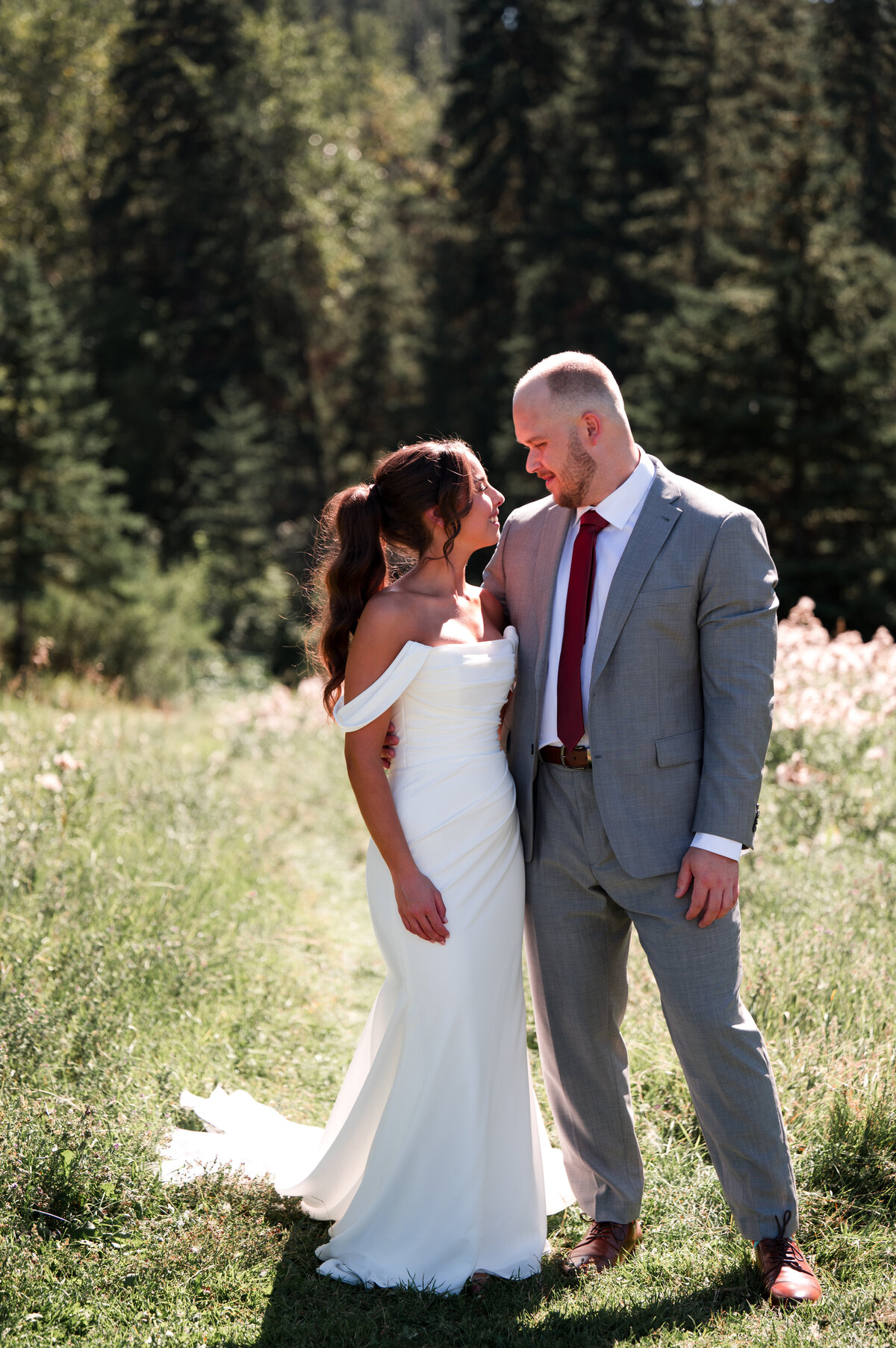 bride and groom stand in a sunny field with wildflowers