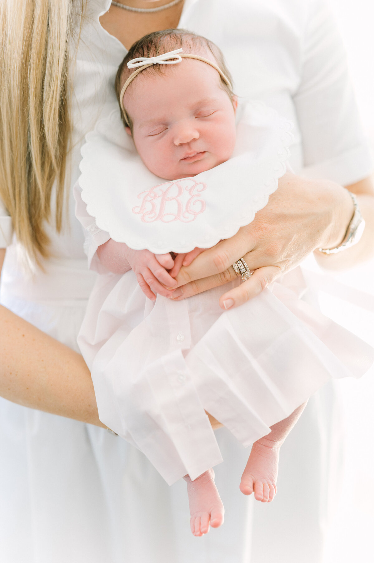 Mother holding a baby  girl wearing a monogramed bib.