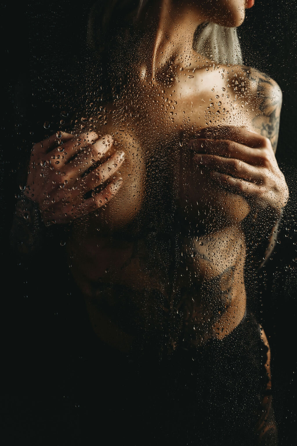 Intimate boudoir shower session with a moody, sensual atmosphere, showcasing elegance and confidence behind the glass.