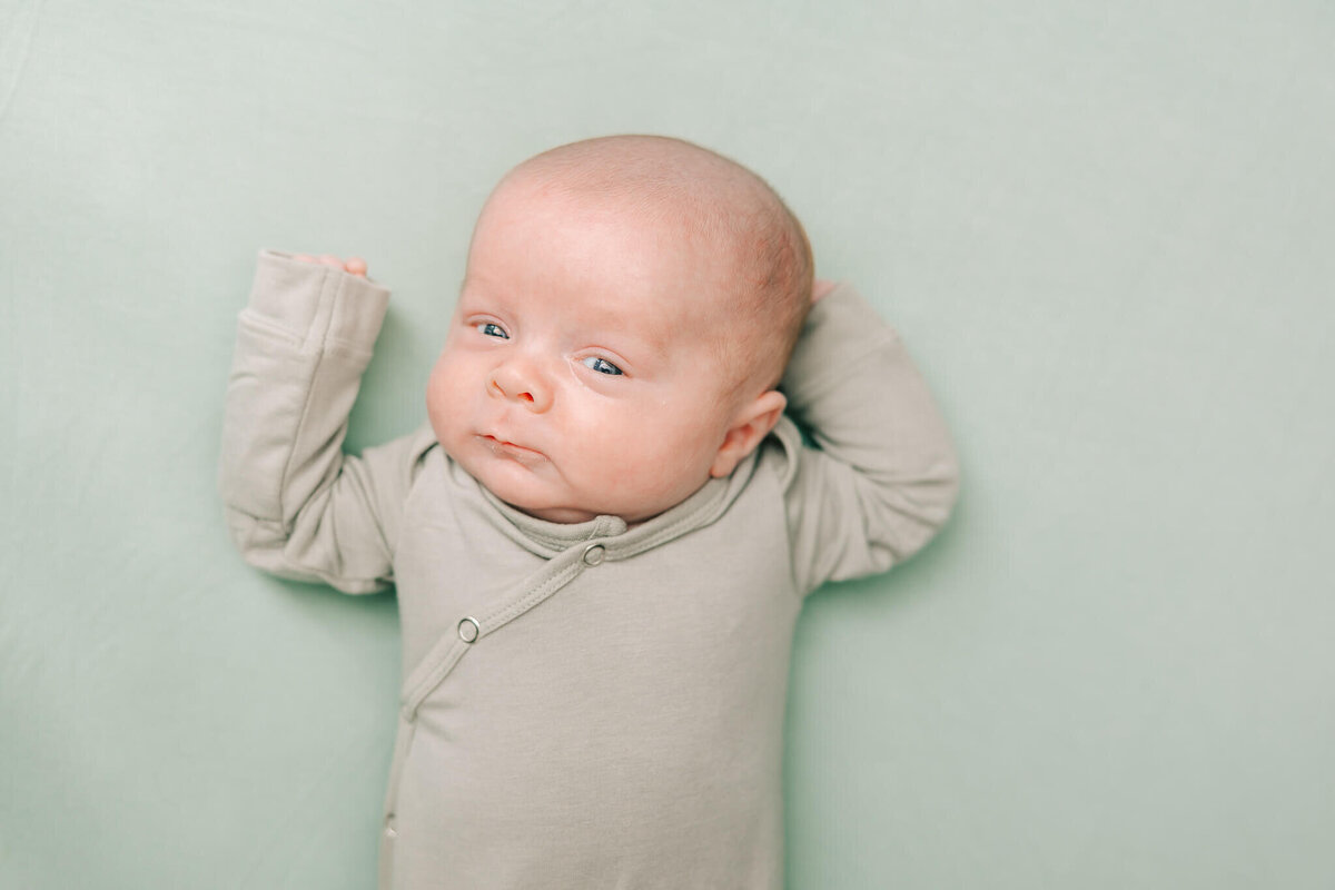 Baby boy wearing an olive knotted gown during his newborn potrait session in North Augusta, South Carolina.