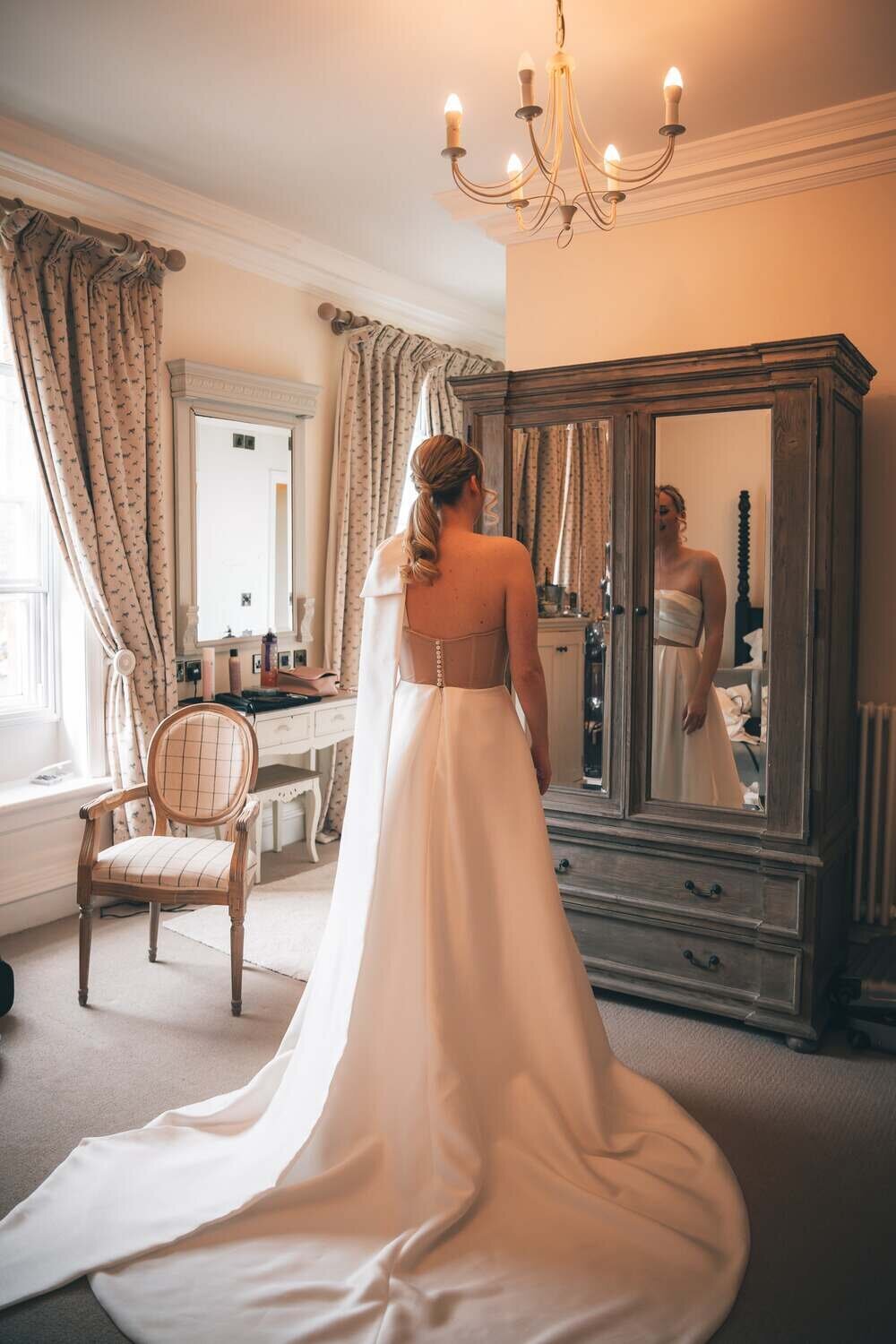 Bride looks into mirror whilst getting ready