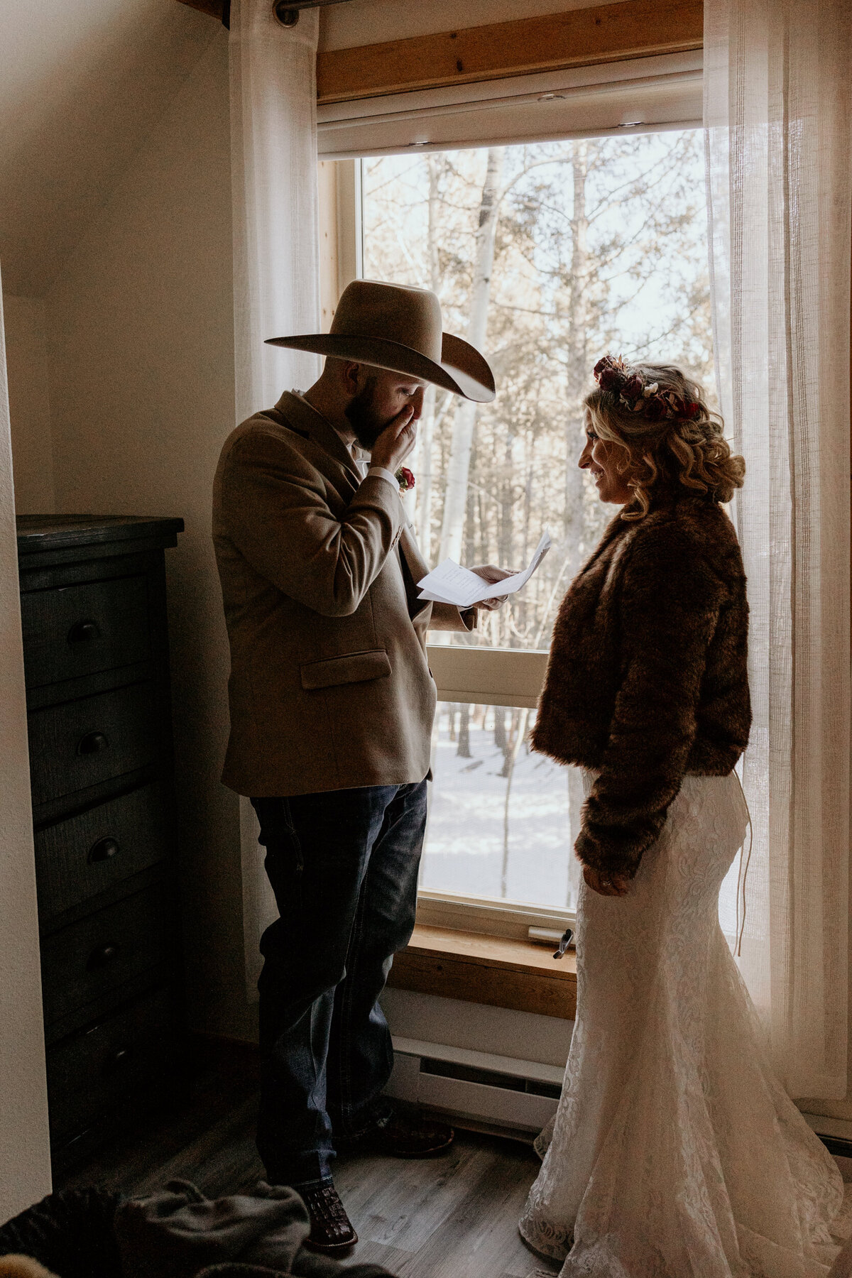 bride and groom exchanging personal vows in front of a window in a cabin