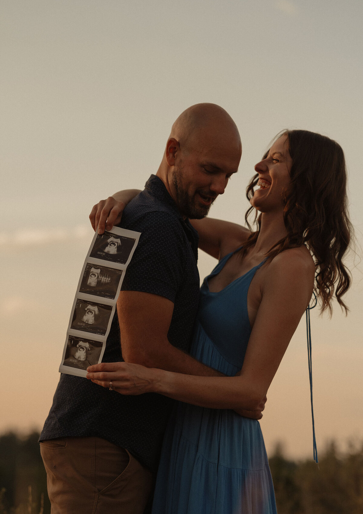 expecting couple sharing ultrasound photos during golden hour sunset in Bend, Oregon